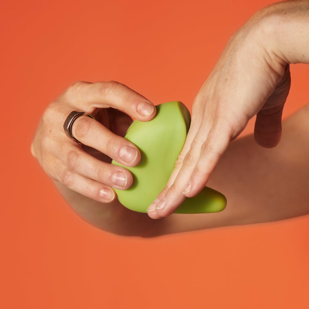 Hands holding the kiwi vibrator to demonstrate how it can be used for shallow penetration for someone who experiences pain during sex