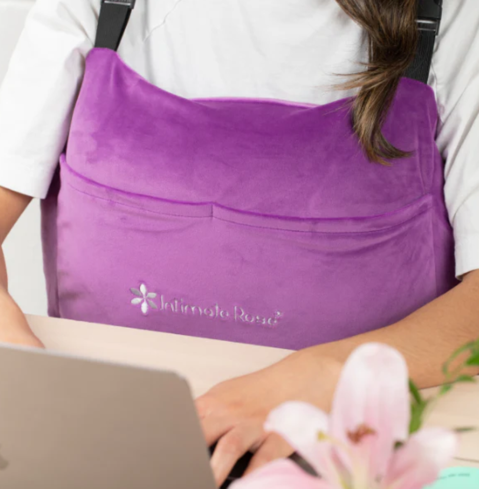 Close up of woman working at a desk on her laptop while wearing an Intimate Rose mastectomy pillow